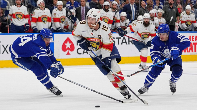 Floridas "Panthers" uzbrucējs Metjū Tkačaks ar ripu, aizsardzībā Ostons Metjūzs (Nr. 34) un Mičels Mārners (Nr. 16). Foto: John E. Sokolowski/USA Today Sports/Scanpix